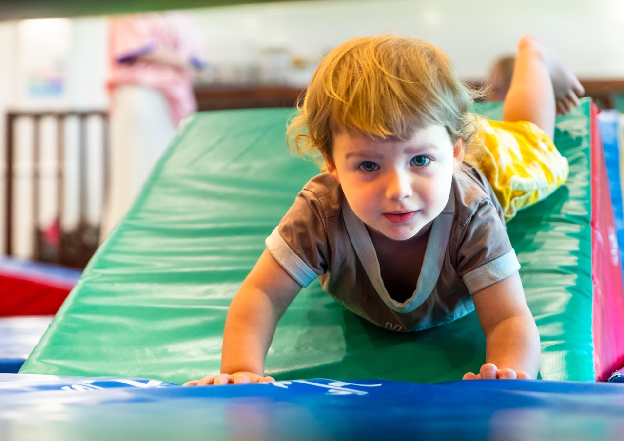 A joyful toddler sliding down a soft obstacle