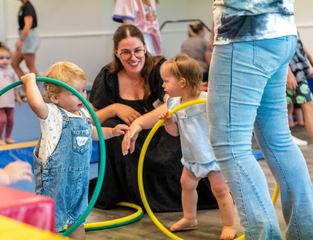 A grown-up and toddlers playing with hoops